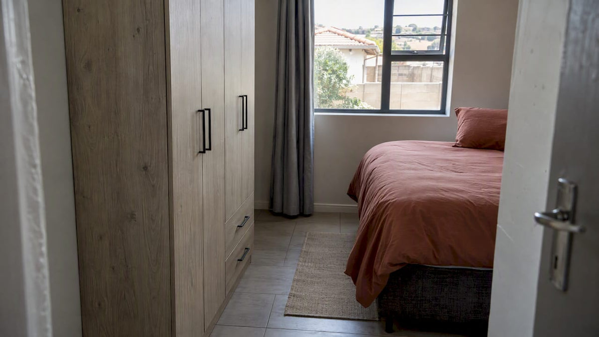 Slim wardrobe beside a narrow bedroom walkway